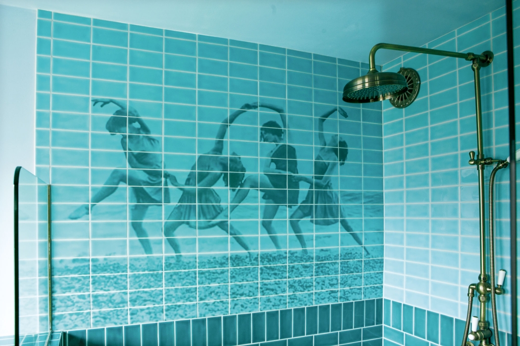 Tegeltableau met vier dansers op blauwe tegels, aangebracht over de hele breedte van de douche door TATTOOtoilet. Tegelzetter: Carin van Dongen.